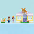 LEGO Friends bunny hotel display showing pastel yellow and lavender plastic bricks forming a finished animal hotel with bunny sign, door, windows, garden base, accessories, and minifigures posed.