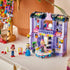 LEGO Friends fashion show display showing lavender and purple plastic bricks forming a finished runway building with rotating stage, balcony, lights, outfit displays, and multiple minifigures posed on a tabletop.