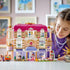 LEGO Friends Heartlake City Grand Hotel play scene shows a child beside the pink, white and lavender hotel facade with figures, elevator, luggage cart and wedding display on a table.