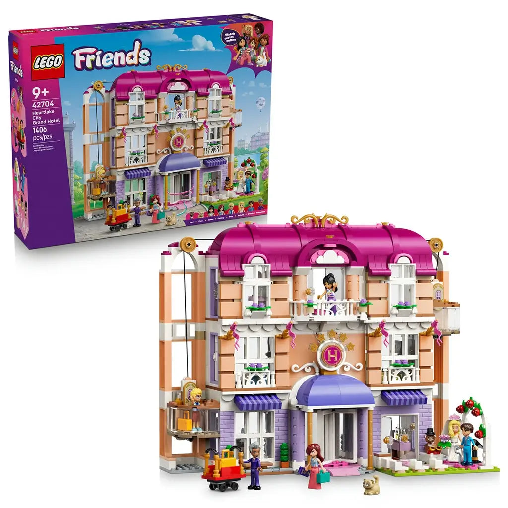 LEGO Friends Heartlake City Grand Hotel set 42704 pairs its retail box with the pink, white and lavender hotel model, featuring balconies, elevator, figures, luggage cart and wedding arch.