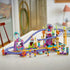 LEGO Friends Mermaid Roller Coaster Ride set 42703 features purple plastic tracks, colorful sea-themed scenery, a coaster train and mini-dolls displayed on a white table.