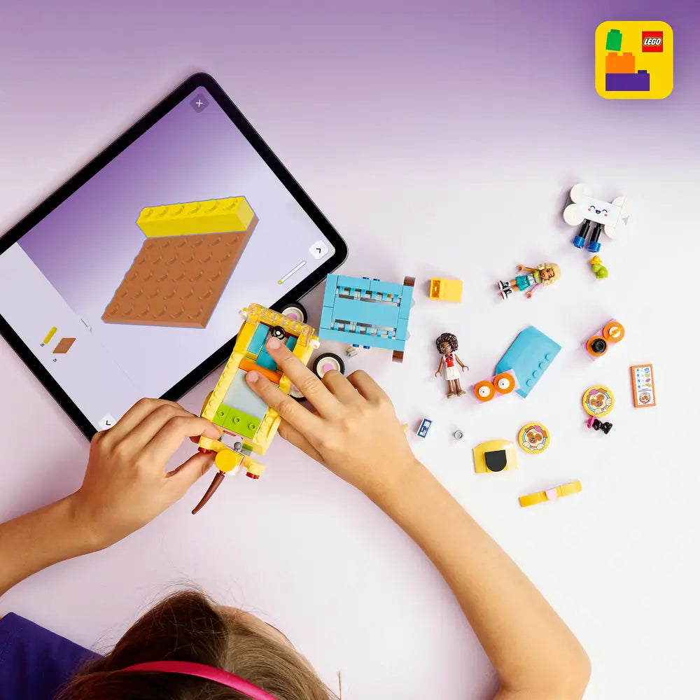 LEGO Friends building toy lifestyle scene with pastel pet van pieces spread on a light surface, showing a child assembling the yellow vehicle, roof, wheels, accessories, pets, and figures using digital instructions.