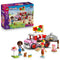 LEGO Friends Pizza Truck 42694 set in pink, red, white and gray plastic, with two mini-dolls, puppy, pizza oven and accessories beside the retail box.