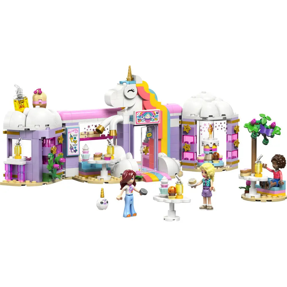 LEGO Friends Unicorn Dream Café playset showing pastel white, pink, and lavender plastic bricks forming a whimsical café with unicorn arch, rainbow details, dessert tables, and minifigures in a fantasy café setting.