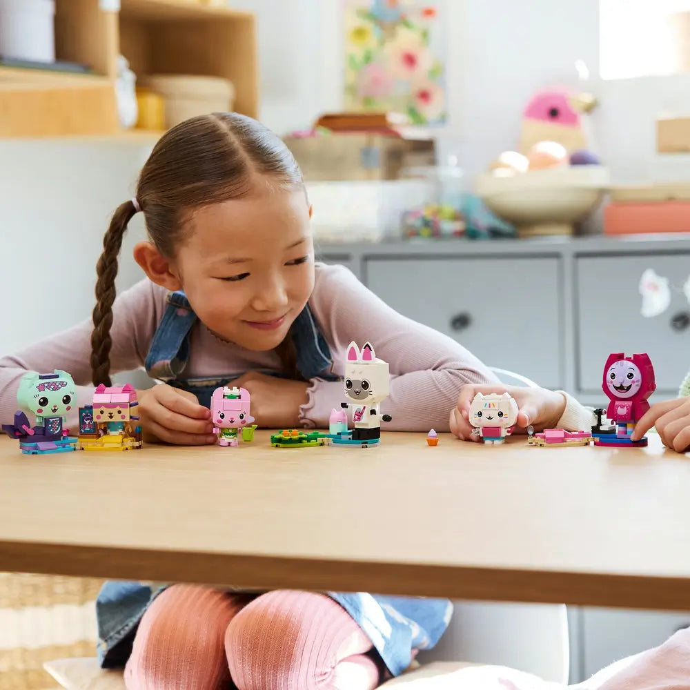 LEGO Gabby’s Dollhouse lifestyle image shows children’s hands arranging pastel brick-built cat characters on a table, demonstrating creative play, building interaction, and imaginative storytelling at home.