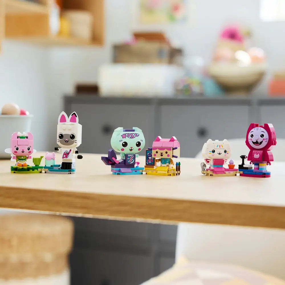 LEGO Gabby’s Dollhouse cat friends displayed shows completed pastel brick-built characters lined up on a tabletop, emphasizing their playful expressions, bright colors, and collectible display appeal.