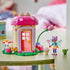 LEGO Gabby's Dollhouse garden house in pink, tan and green plastic bricks, displayed with mushroom roof, pink door, fairy and cat figures, flower stem and watering can.