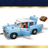 LEGO Harry Potter Enchanted Flying Ford Anglia toy car in light blue plastic with opening doors, white roof, rounded headlights, and ejecting trunk feature, shown with a brown Hogwarts trunk accessory on a white background.