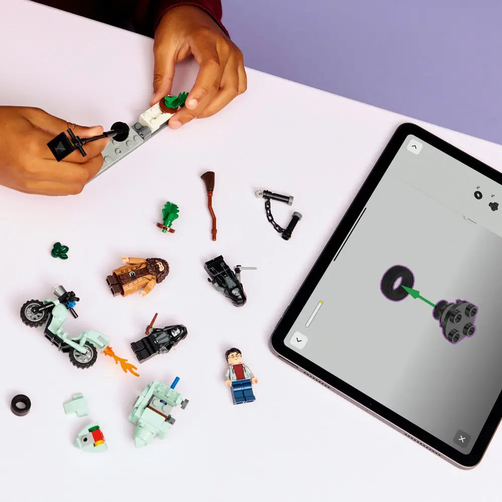 LEGO Harry Potter building experience shows colorful plastic bricks, minifigures, and accessories spread across a light tabletop while hands assemble street details and characters using clear digital instructions on a tablet screen.