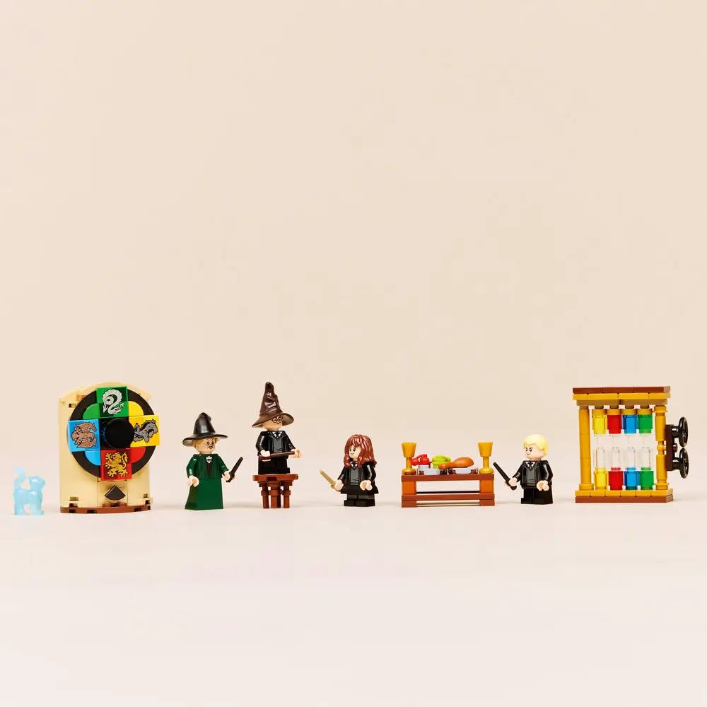 LEGO Harry Potter minifigure display features multicolor plastic figures with smooth molded textures arranged in a straight line, showing the Sorting Hat wheel, students, house accessories, and potion elements against a clean studio background.