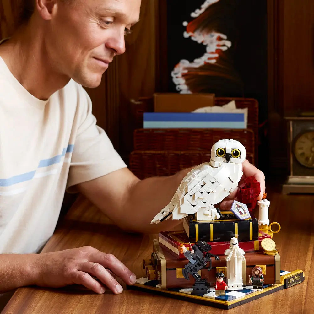 Adult assembling LEGO Harry Potter Philosopher’s Stone display model made of white and brown plastic with Hedwig owl, carefully placing pieces by hand to highlight focused building and premium collectible construction.
