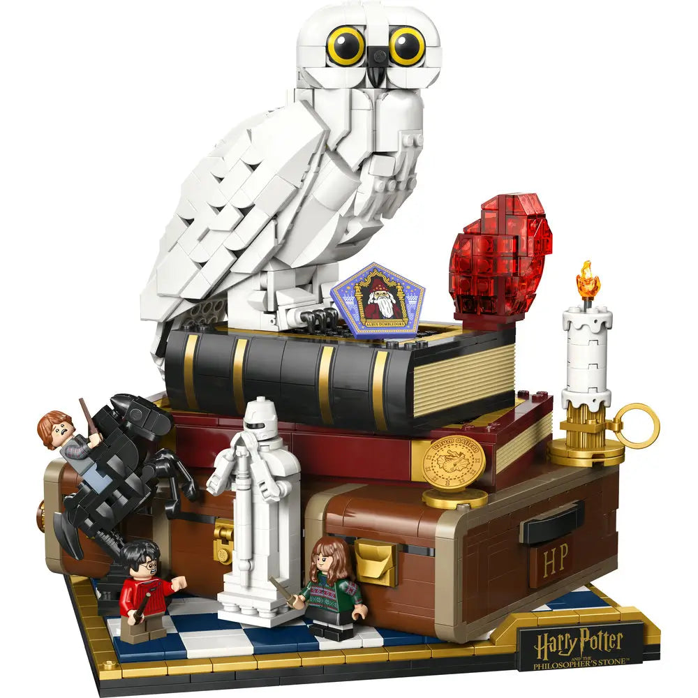 LEGO Harry Potter Philosopher’s Stone display model in white, red, brown, and gold plastic featuring Hedwig owl perched on stacked books, layered sculpted feathers, magical artifacts, and minifigures arranged on a decorative display base.