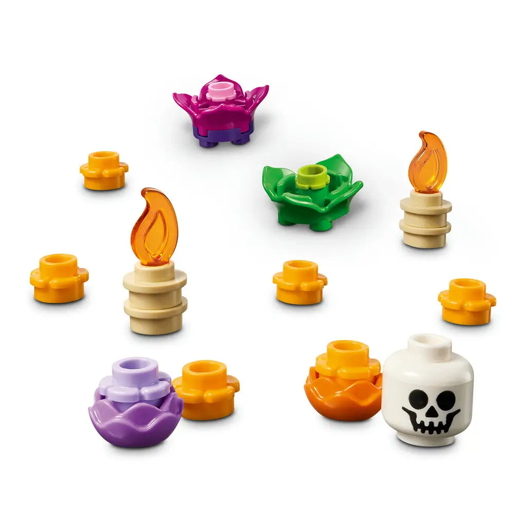 LEGO Altar of the Dead accessories include orange offerings, purple and green flower pieces, two tan candles with flames, and a white skull piece on a white background.
