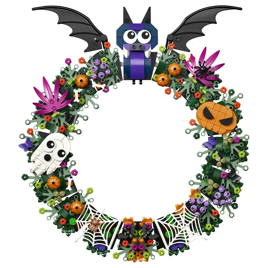 LEGO Halloween wreath in green plastic bricks forms a round decoration with a black-winged bat, white ghost, orange pumpkin, purple flowers, spiders, and white spiderwebs.