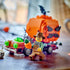 LEGO Jack-O'-Lantern Pickup Truck scene shows a brown brick vehicle with a large orange pumpkin, black spider, green lights, and farmer minifigure on a wooden tabletop.