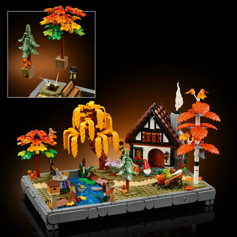 LEGO autumn cottage garden scene shows multicolored plastic trees, a small house, flowing stream, and garden details with layered textures, presented as a complete decorative display on a neutral studio background.