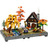 LEGO autumn cottage garden diorama features warm orange, yellow, and green plastic elements with textured brick details, forming a rustic cottage, trees, stream, and plants displayed as a decorative seasonal scene.