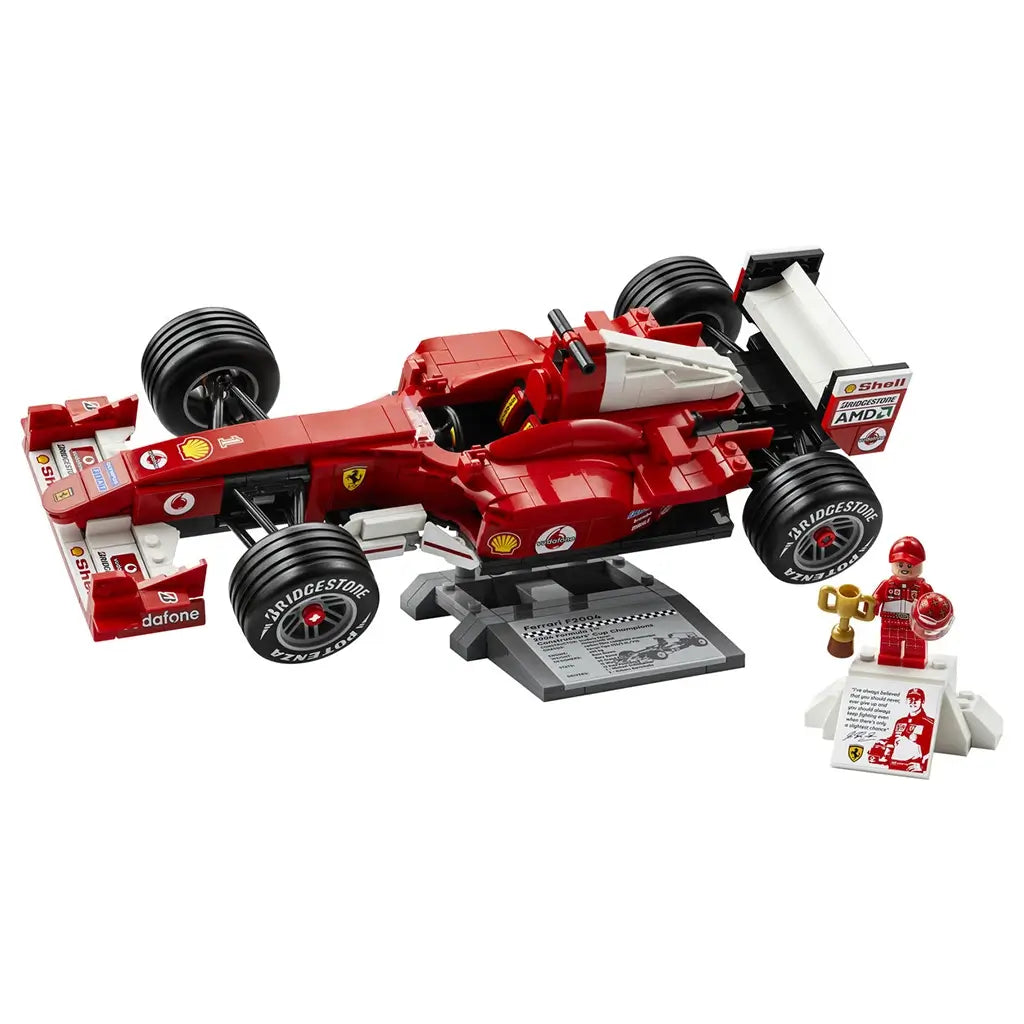 LEGO Ferrari F2004 model showcases red plastic Formula 1 race car with smooth aerodynamic body, black tires, and white accents, designed as detailed collectible displayed on stand against clean background.