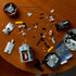 LEGO Icons Hubble Space Telescope set is shown partly assembled in gray, black and gold plastic bricks, with blue solar panels and loose pieces spread across a wood table.