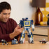 Person assembling the LEGO Icons Transformers Soundwave set, showing the blue and gray robot model with articulated limbs and accessories including cassette builds and a display plaque.