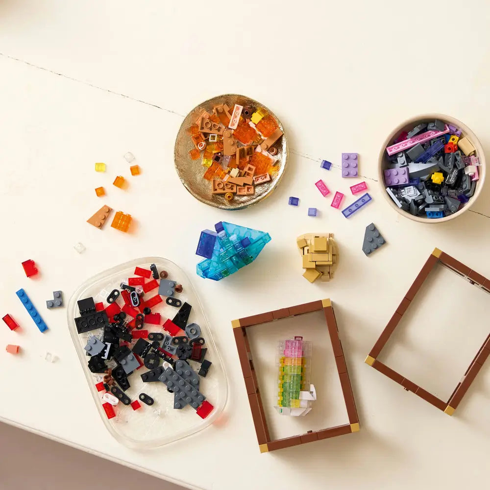 Assorted LEGO mineral pieces spread across a table, including colorful translucent orange, purple, and blue crystal bricks and rectangular brown frame components.