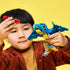 LEGO Jurassic World Baby Dinosaur Pteranodon toy shows a child holding the blue and tan brick-built flying dinosaur and a red seafood piece against a bright yellow background.