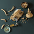 LEGO Jurassic World Triceratops fossil set uses tan plastic bricks shown partly assembled from above, with skeletal sections, minifigure, plaque and loose pieces on a table.