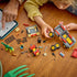 LEGO Jurassic World Young T. rex building set spreads red, gray and tan truck parts, ATV, minifigures and green dinosaur across a wooden table as a child assembles it.