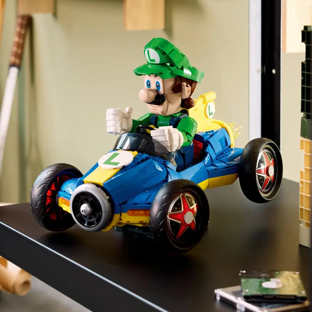LEGO Mario Kart Luigi & Mach 8 collectible display features green, blue and yellow plastic construction, a kart racing form with large wheels and character driver, showcased on a desk in a home setting.