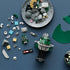 LEGO Marvel Doctor Doom Bust pieces in dark green, silver, gray and black surround a partly assembled model and minifigure on a blue work surface during building.