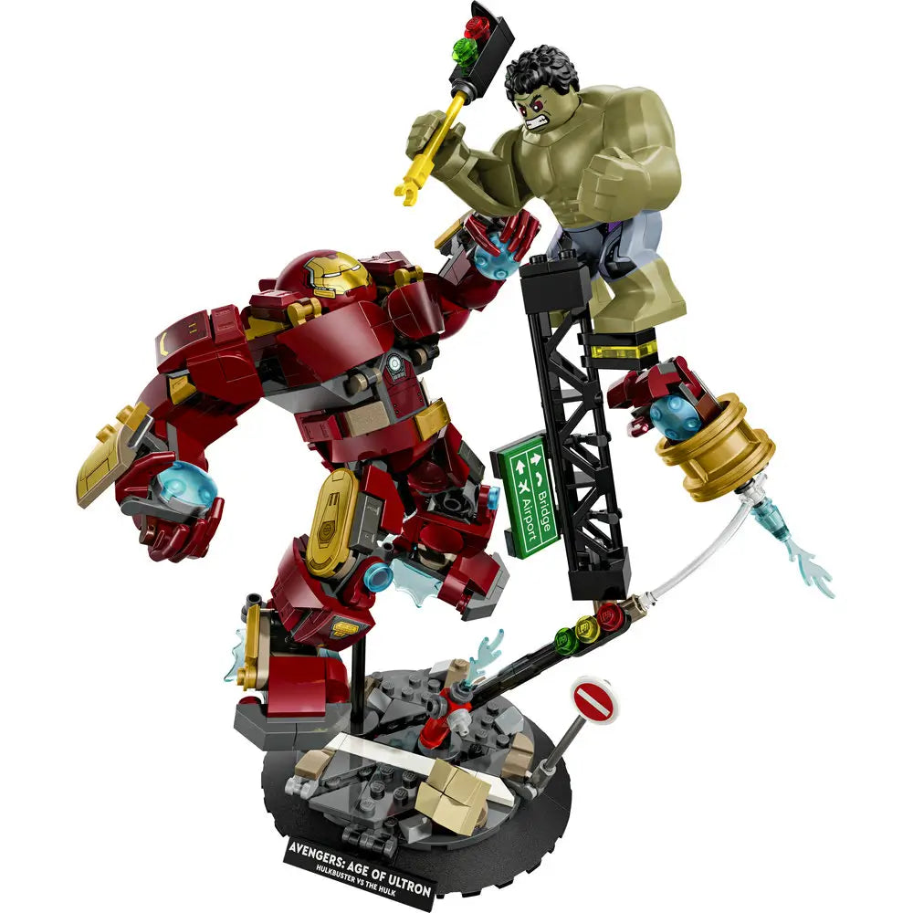 LEGO Marvel Hulkbuster vs Hulk display shows red and gold plastic Hulkbuster armor with bulky mechanical textures battling a green Hulk figure, posed dynamically on a detailed rubble base inspired by Avengers: Age of Ultron.