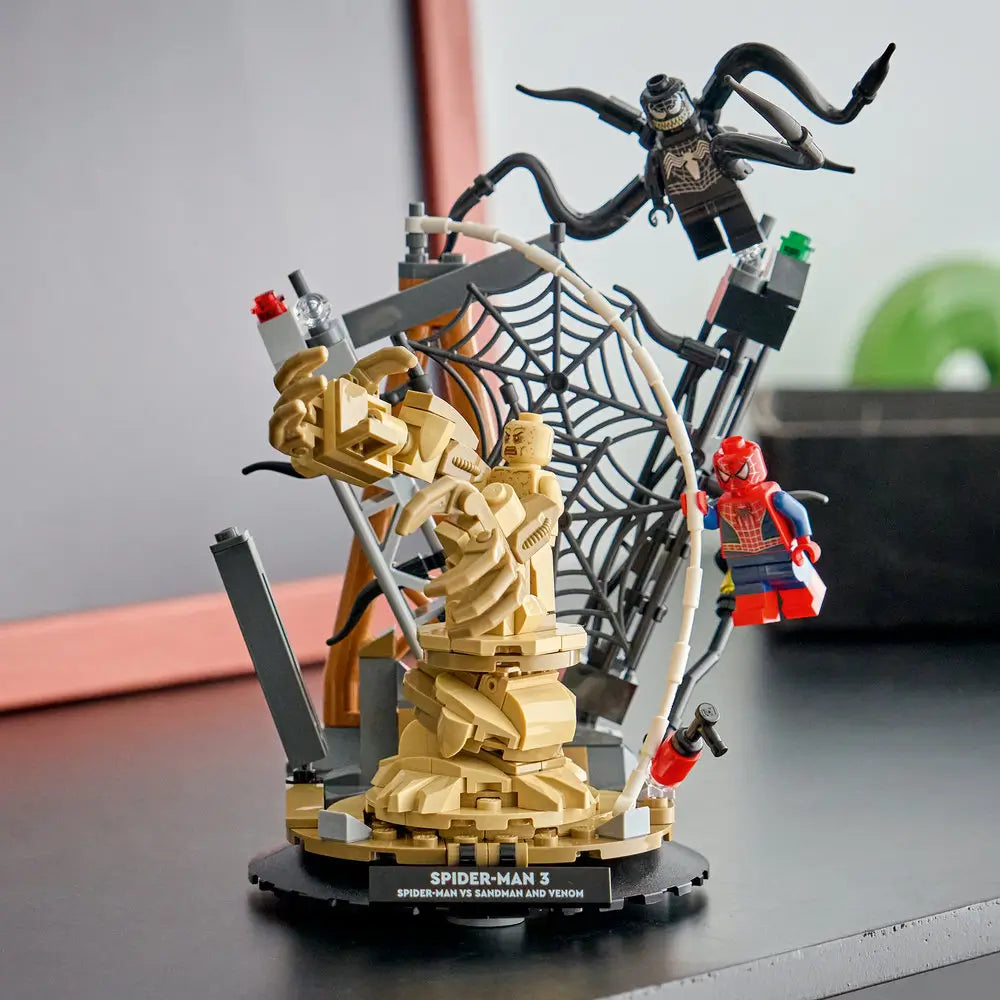 LEGO Marvel Spider-Man 3 display setup with the completed Sandman and Venom scene on a round base, featuring tan rock textures, black tentacles, and Spider-Man swinging on a web strand.