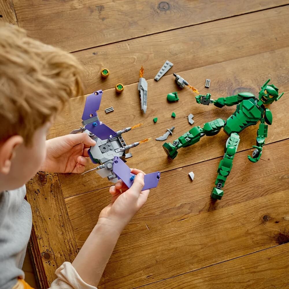 Boy playing LEGO® Marvel Green Goblin Construction Figure 471 Piece Building Set (76284) on table with pieces scattered