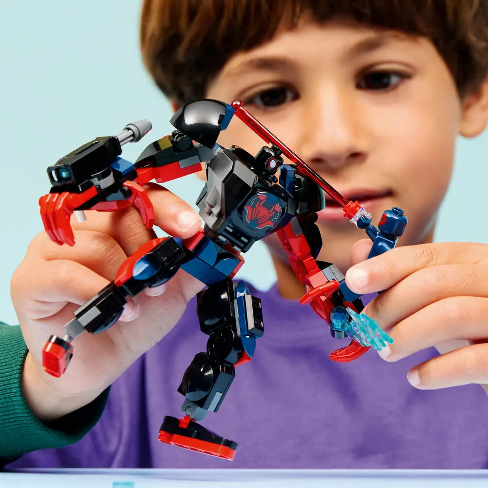 LEGO Marvel Spider-Man mech action figure held by a child, featuring black and red articulated armor, clawed hands, and web accessories, emphasizing imaginative play and scale against a soft blue background.