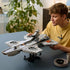LEGO Marvel Helicarrier collectible, gray plastic aircraft-carrier model with detailed runway and rotor assemblies, presented on a stand as a builder admires it across a tabletop setting.