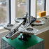 LEGO Marvel S.H.I.E.L.D. Helicarrier display model, gray plastic aircraft-carrier build with detailed deck and rotor sections, showcased on a stand near large windows in a modern interior.