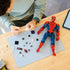 LEGO Marvel Spider-Man construction set, red and blue plastic articulated figure with detachable accessories and web elements, shown during assembly on a cutting mat workspace.