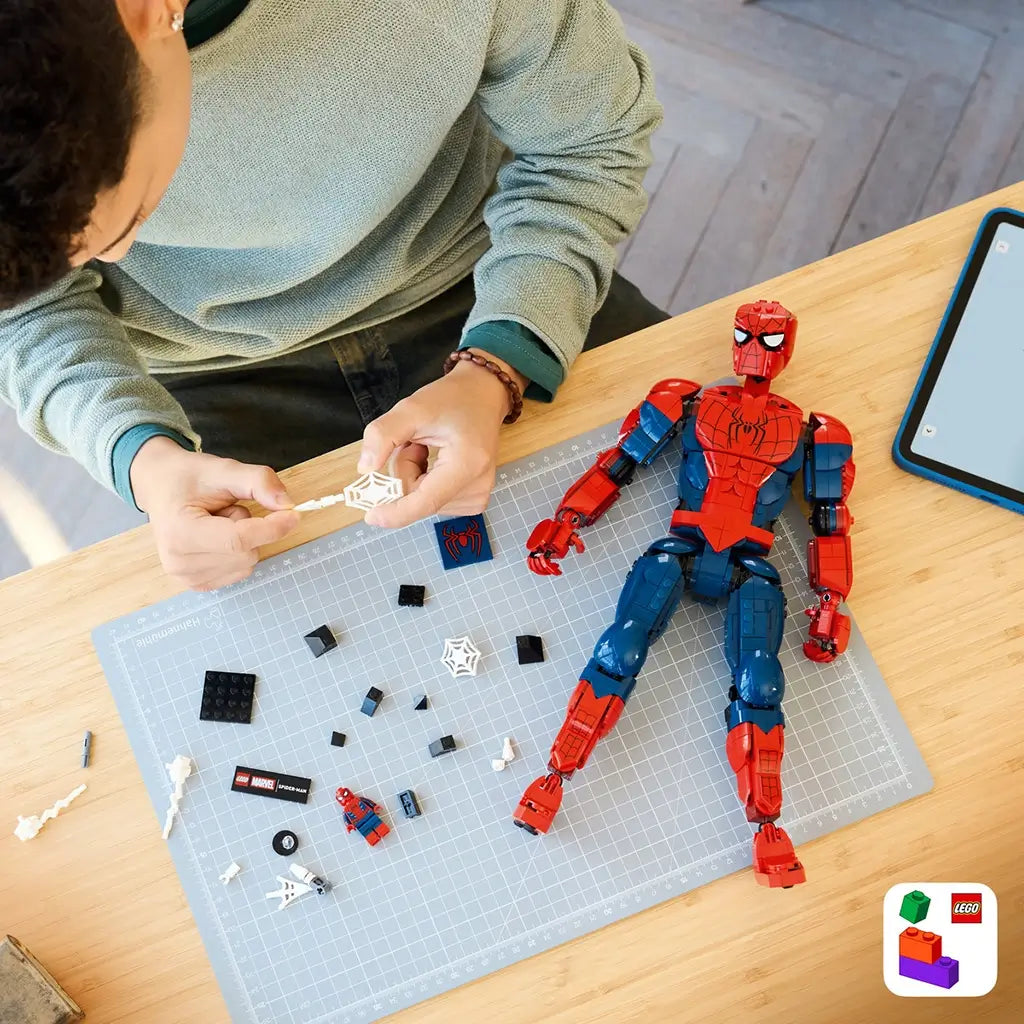 LEGO Marvel Spider-Man building toy, red and blue plastic articulated superhero figure with detailed suit design, web accessory and assembly components on a tabletop background.