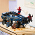 LEGO Marvel prison transport vehicle, blue plastic armored truck with detailed grille, large tires and superhero characters, displayed on a tabletop with web accessories and action elements.