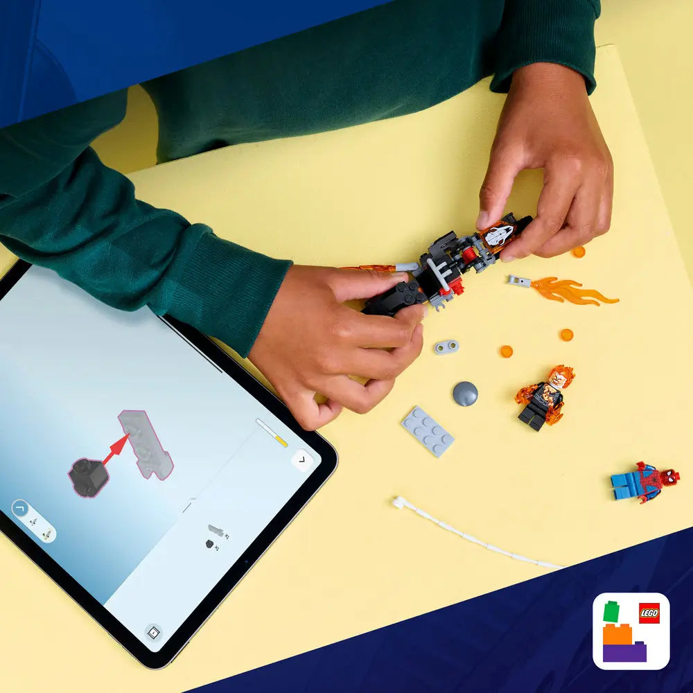 LEGO Marvel Spider-Man motorcycle building set viewed from above, showing black and gray bike pieces, flame elements, minifigures, and parts arranged on a yellow surface beside a tablet with digital step-by-step instructions.
