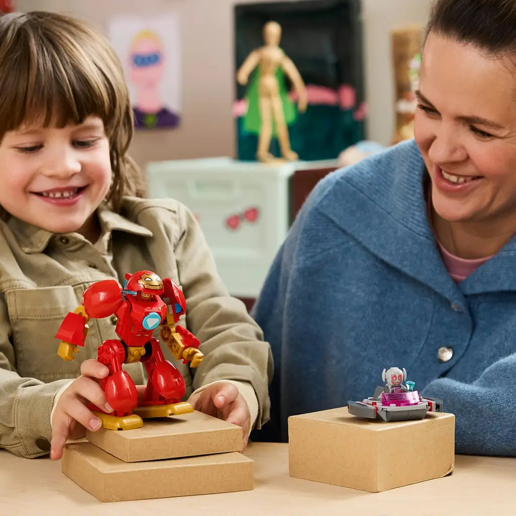 LEGO Marvel Ultron vs. Iron Man playset in red, gold, gray, and pink plastic is displayed as a smiling child holds the Iron Man mech beside an adult and Ultron craft.