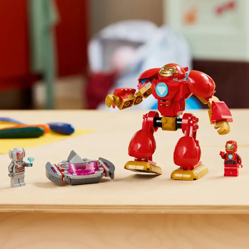 LEGO Marvel Ultron vs. Iron Man set in red, gold, gray, and pink plastic is displayed on a table with the large Iron Man mech, Ultron flying craft, and two figures.