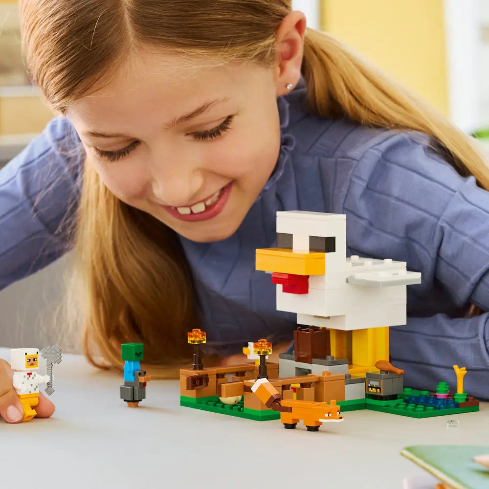 LEGO Minecraft Chicken Farm lifestyle builder image showing a child assembling a white and yellow plastic brick chicken, cubic block form for creative play, arranged on a table with figures and accessories.