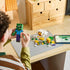 LEGO Minecraft Chicken Jockey building set uses green, white and yellow bricks as a builder assembles the zombie beside a chicken, chick, loose pieces and digital instructions.