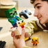 LEGO Minecraft Chicken Jockey build in white, green and yellow bricks is held by a smiling builder, with a zombie riding the large chicken and a baby chick on a wood desk.
