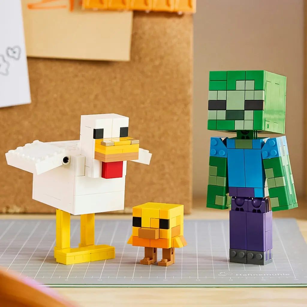 LEGO Minecraft Chicken Jockey figures in white, yellow, green, blue and purple bricks show a large chicken, baby chick and zombie posed on a gray craft mat indoors.