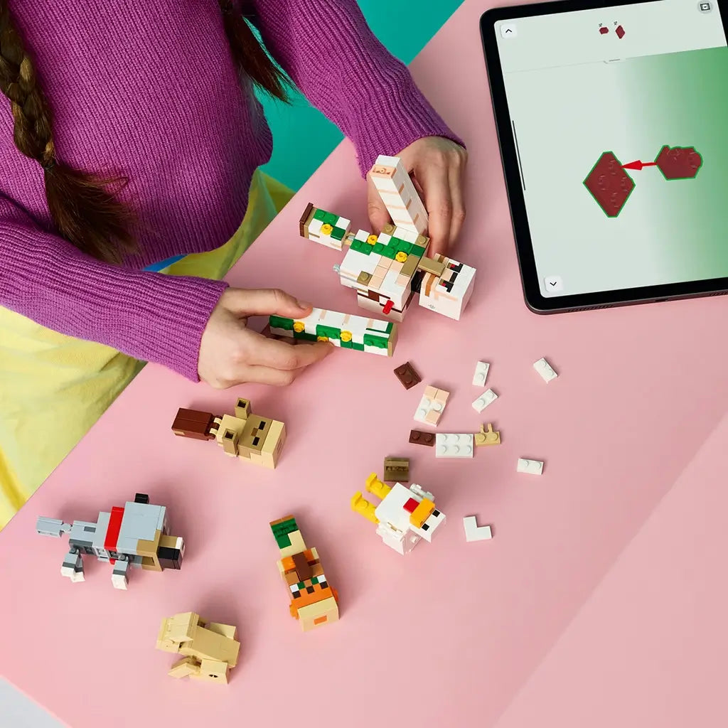 LEGO Minecraft Chicken Jockey Desert Attack build uses white, green and tan bricks as a child assembles the Iron Golem beside loose figures and tablet instructions.