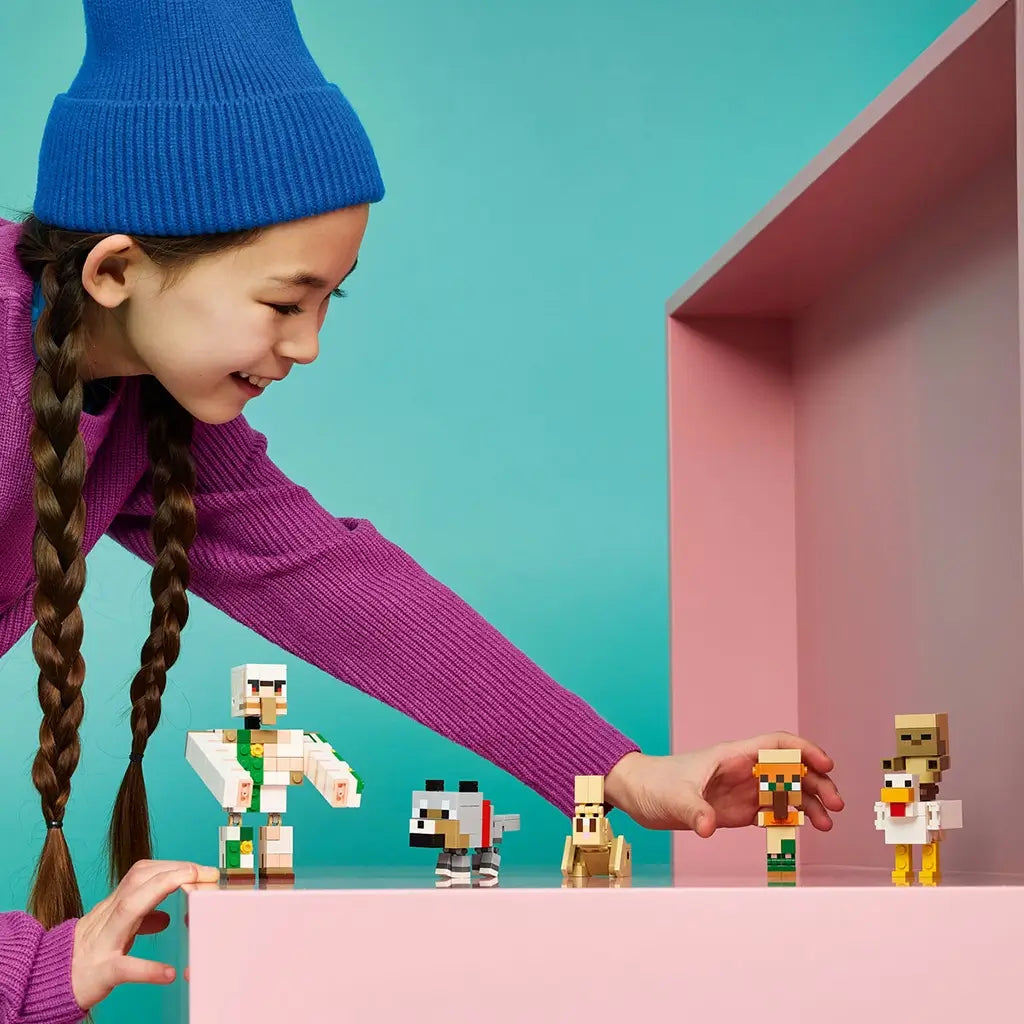 LEGO Minecraft Chicken Jockey Desert Attack figures in white, tan and gray bricks are arranged by a smiling child on a pink shelf against a bright turquoise backdrop.
