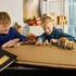 LEGO Minecraft Evoker Village Attack in brown, tan and green bricks is arranged across a tabletop as two smiling children play with village figures and structures.