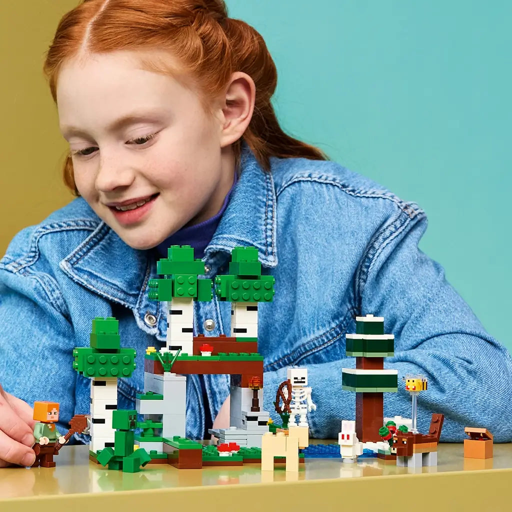 LEGO Minecraft First Night Adventure set features green, white and brown forest scenery with Alex, a Creeper, skeleton and animals as a child plays at a table.